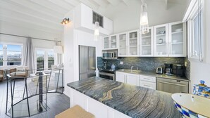 A modern kitchen with a marble countertop, stainless steel appliances, and a city view.