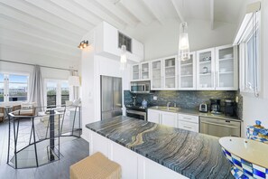 A modern kitchen with a marble countertop, stainless steel appliances, and a city view.