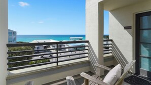 A balcony with a view of the ocean, a chair, and a sign that says "Close to the Beach."