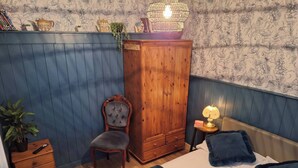 A bedroom with a bed, a wooden wardrobe, a chair, a bedside table with a lamp, and a small plant. - Ouston Oasis, Beamish (Chester-le-Street)