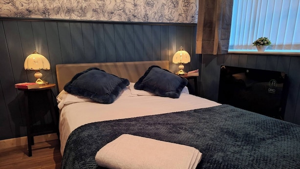 A neatly made bed with two pillows, a folded blanket, and two bedside lamps on wooden nightstands. - Ouston Oasis, Beamish (Chester-le-Street)