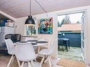 Eine moderne Küche mit Kühlschrank, ein Essbereich mit Tisch und Stühlen, einer hängenden Pendelleuchte und einem farbenfrohen abstrakten Gemälde an der Wand.