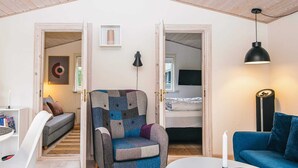 A room with a sofa, a chair, a table, a lamp, and a bed. - 4 Star Holiday Home in Hovborg (Hovborg)