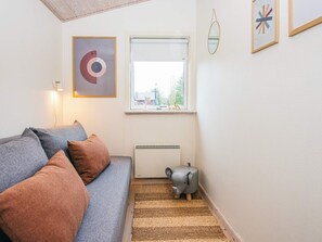 A cozy living room with a grey sofa, a radiator, a window with a view, and a small elephant-shaped stool. - 4 Star Holiday Home in Hovborg (Hovborg)