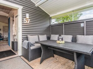 A covered patio area with a dark-colored wicker sofa and a matching table, number 57 displayed on the wall, and a clear view of the outside. - 4 Star Holiday Home in Hovborg (Hovborg)