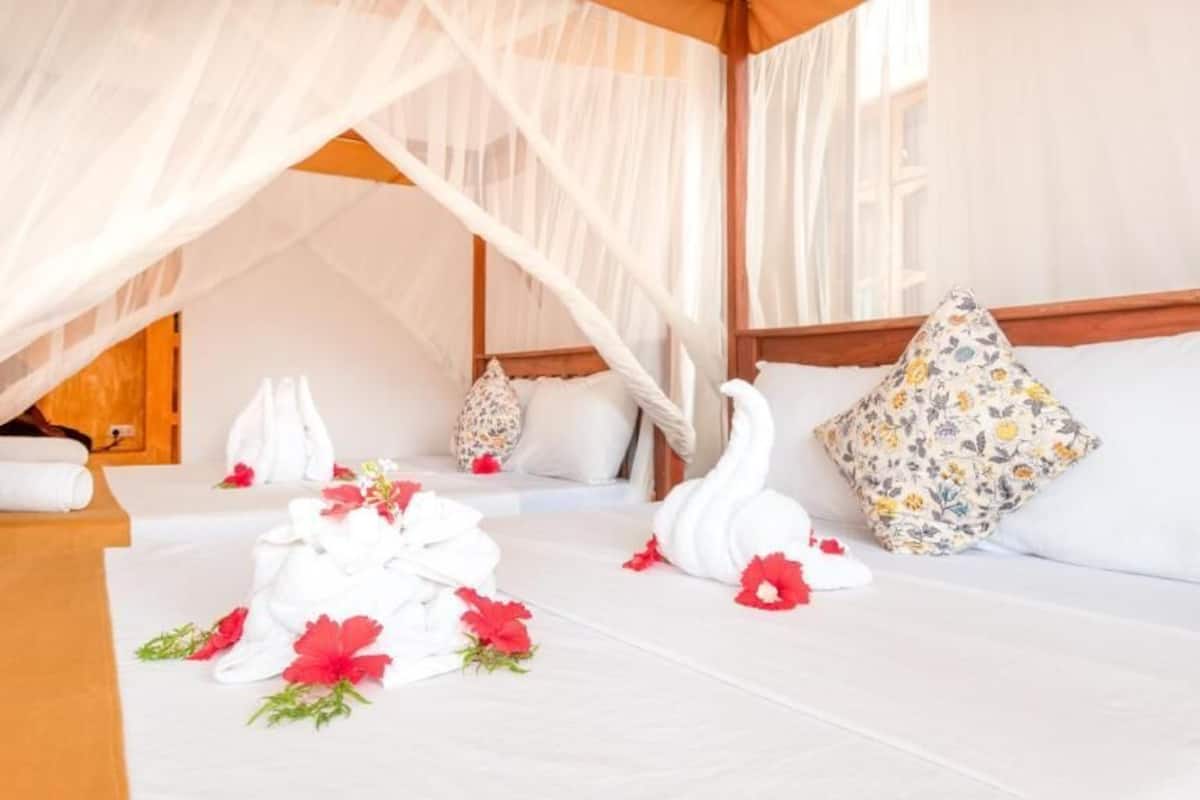 A neatly made bed with white linens, a floral pillow, and a swan-shaped pillow.