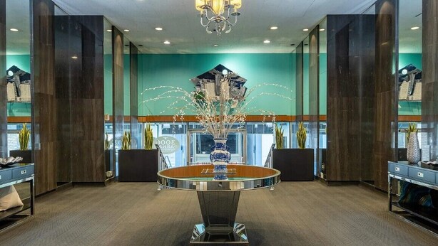 Eine Lobby mit einem runden Tisch in der Mitte, hohen Holzsäulen und einem Kronleuchter.