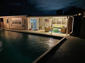 A poolside area with a house-like structure, including a door, windows, and outdoor furniture. - Happy OURS 206–Pool Near Beach–Sleeps 6 (Panama City Beach)