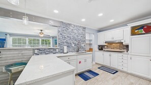 Una cocina moderna con armarios blancos, salpicadero de azulejos y una isla grande.