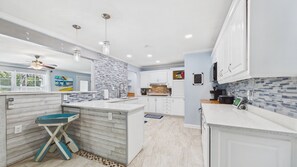 A modern kitchen with white cabinetry, a central island, and a blue accent wall.