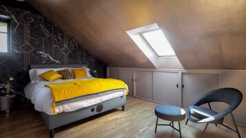 Un dormitorio con cama, tragaluz, silla y escritorio.