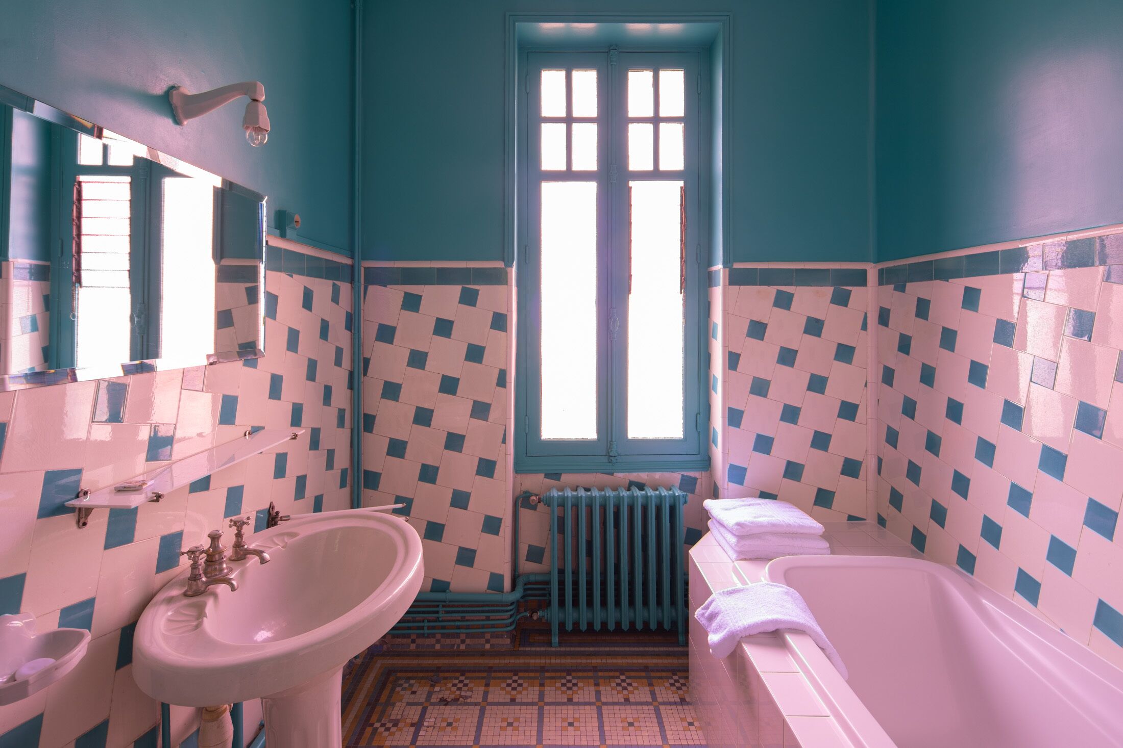 A bathroom with a sink, bathtub, and window.