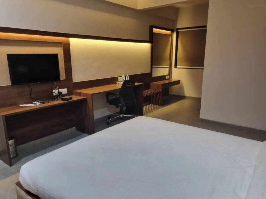 Habitació d'hotel amb un llit, una taula, una cadira, un televisor i un mirall.