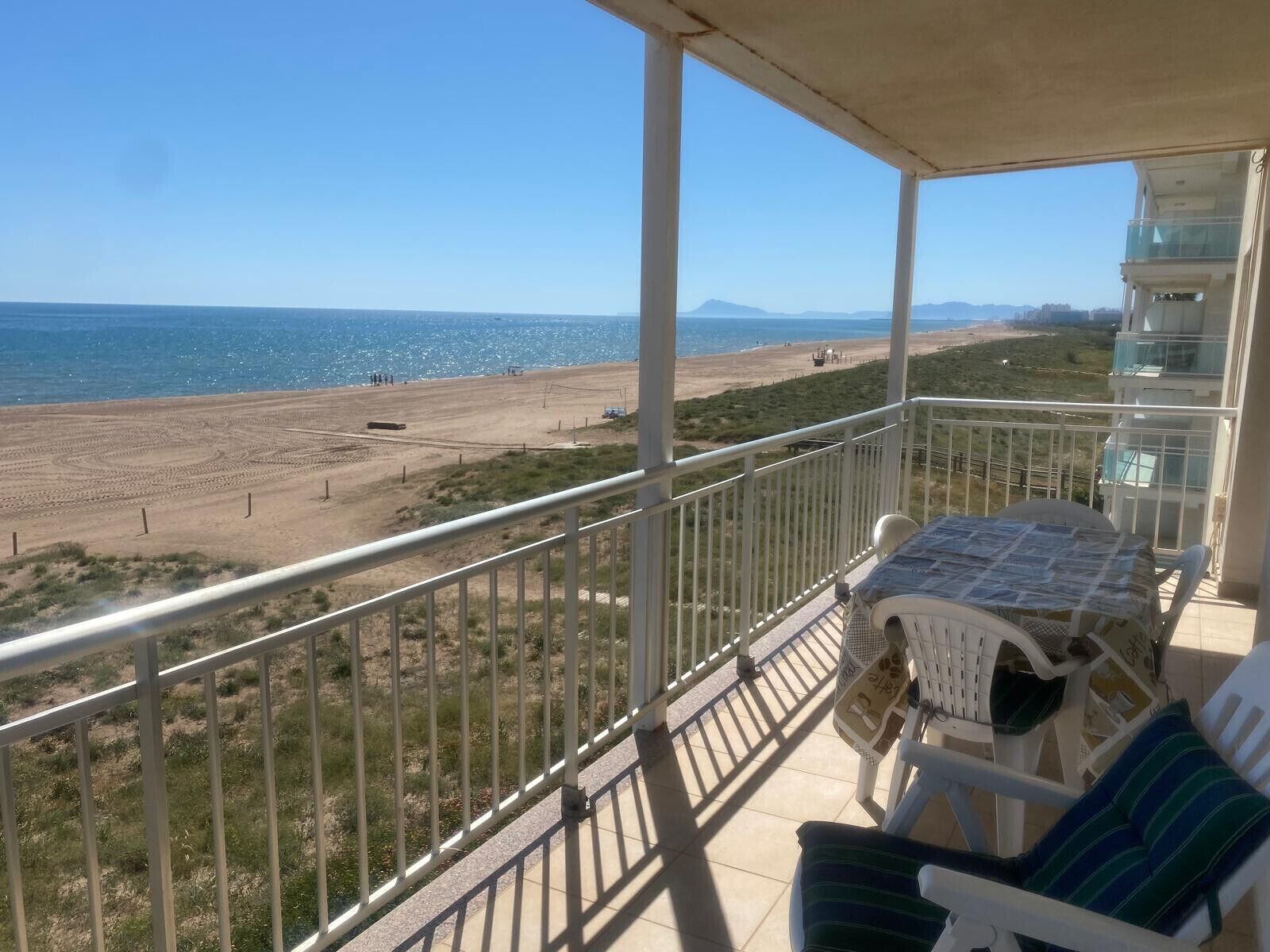 A balcony with a view of a beach and the sea.