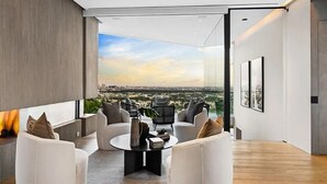 Een moderne woonkamer met een panoramisch stadszicht, met een zithoek en een salontafel.