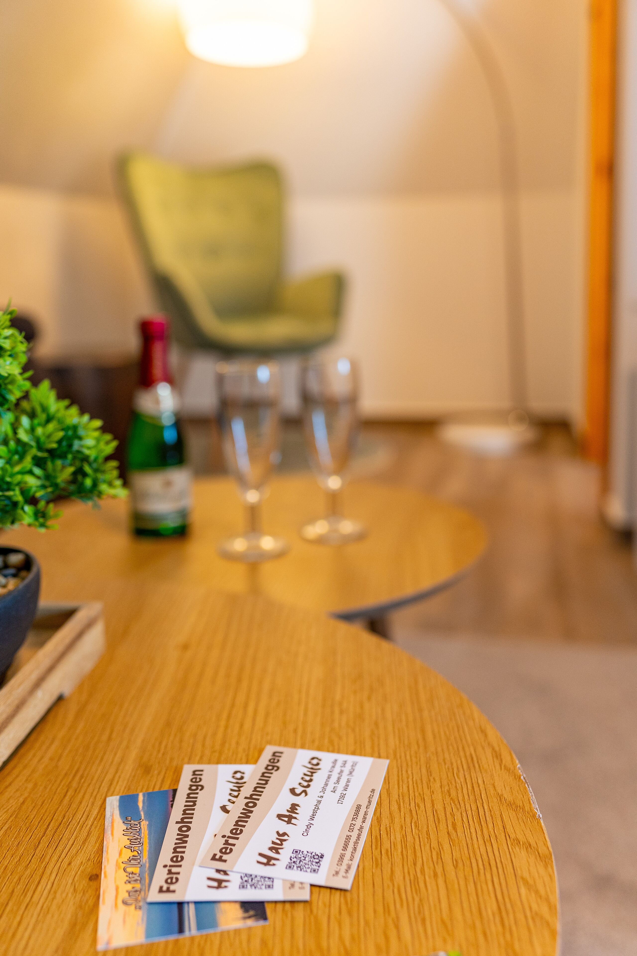 Una mesa de madera con folletos y una botella de champán.