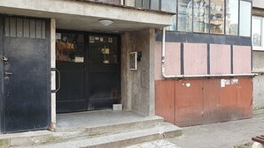 A building entrance with a black door, a small set of steps, and a visible security camera above the door. - Apartment for guests Krasy (Ruse)