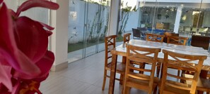 Enjoy dining al fresco in this inviting outdoor space surrounded by lush gardens and a clear sky.