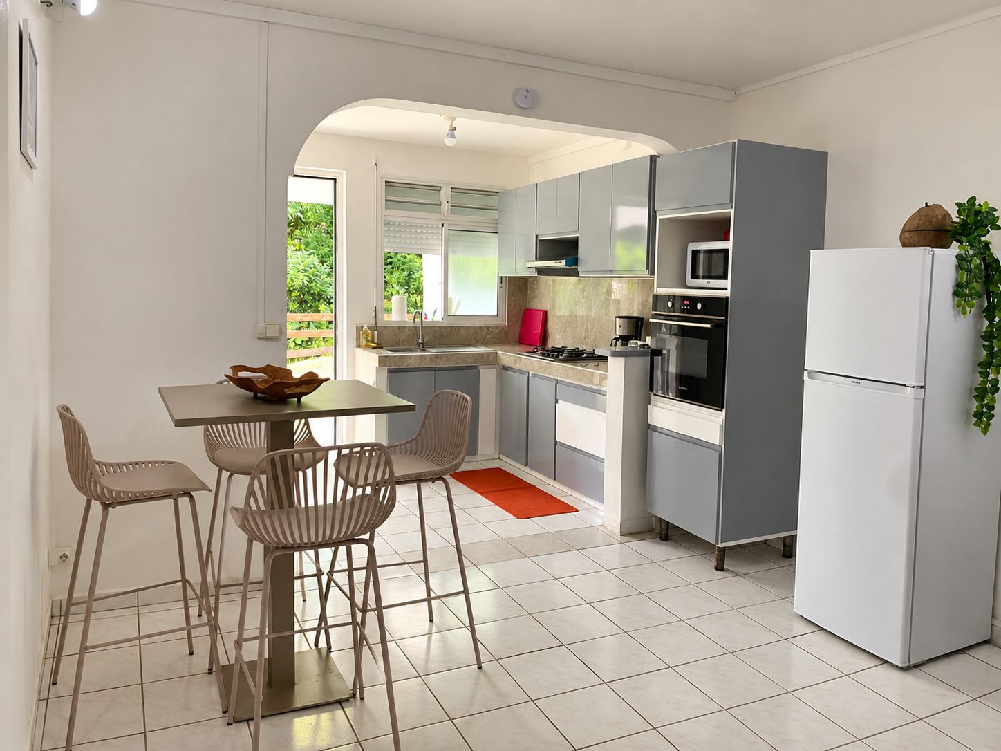 Une cuisine moderne avec des meubles de couleur grise, une table à manger avec des chaises et un réfrigérateur.