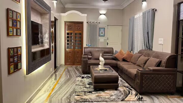A modern living room with a marble floor, a brown leather sofa, a coffee table, and a TV mounted on the wall. - lg signature stays (Bangalore)