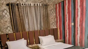 A hotel room with two beds, a wooden headboard, patterned curtains, and a striped wall. - lg signature stays (Bangalore)