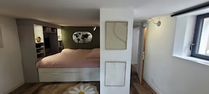 Une chambre à coucher comprenant un lit, une armoire, une œuvre d’art représentant une carte du monde, un tableau abstrait encadré et une fenêtre.