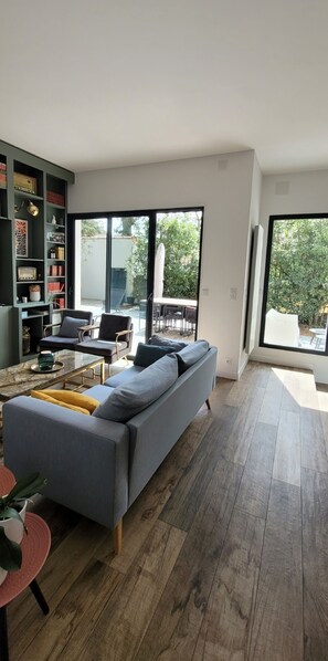 Un salon moderne avec un canapé gris, une table basse et une bibliothèque.