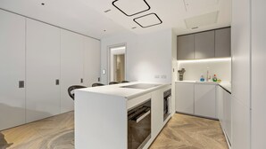 A modern kitchen with a central island, built-in appliances, and a herringbone wood floor. - Spacious Central Flat with Central A/C (London)