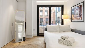 A hotel room with a bed, a mirror, a door to an outdoor balcony, and a framed picture on the wall. - Spacious Central Flat with Central A/C (London)