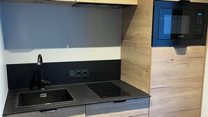 Eine moderne Küche mit Holzausstattung, einer schwarzen Arbeitsplatte, einer eingebauten Mikrowelle und einem Spülbecken.
