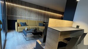Ein modernes Wohnzimmer mit einer Couch, einem Couchtisch und einer einzigartigen Bar aus Holz mit Hockern.