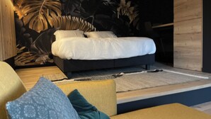 Ein modernes Schlafzimmer mit Bett, einer Couch und einem großen Wandbild.
