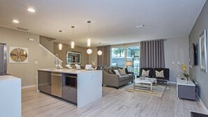 Ein modernes Wohnzimmer mit Sofa, Couchtisch und einer Küchenzeile inklusive Geschirrspüler.