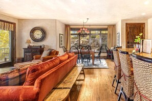A spacious living area with a sofa, dining table, chairs, and a bar area.
