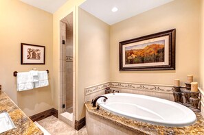 A bathroom with a freestanding bathtub, a shower, and a framed landscape painting.