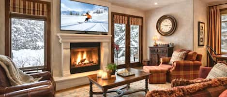 A cozy living room with a fireplace, a television, and a view of a snowy landscape.