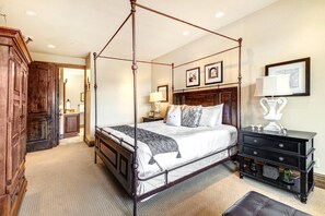 A four-poster bed with a wooden headboard, a bedside table with a lamp, and a large mirror.