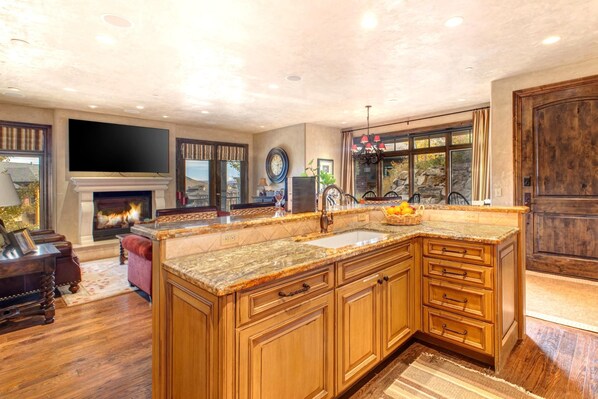 A spacious kitchen with wooden cabinets, a large island, and a fireplace.
