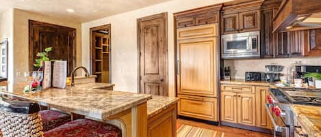 Una cocina amplia con armarios de madera, encimera de granito y microondas integrado.