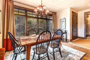 A dining area with a wooden table, black chairs, and a chandelier.