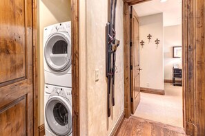 A hallway with wooden doors leading to a laundry room containing two washing machines.