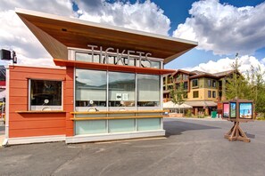 A ticket booth with a clear sign, large windows, and a wooden roof.