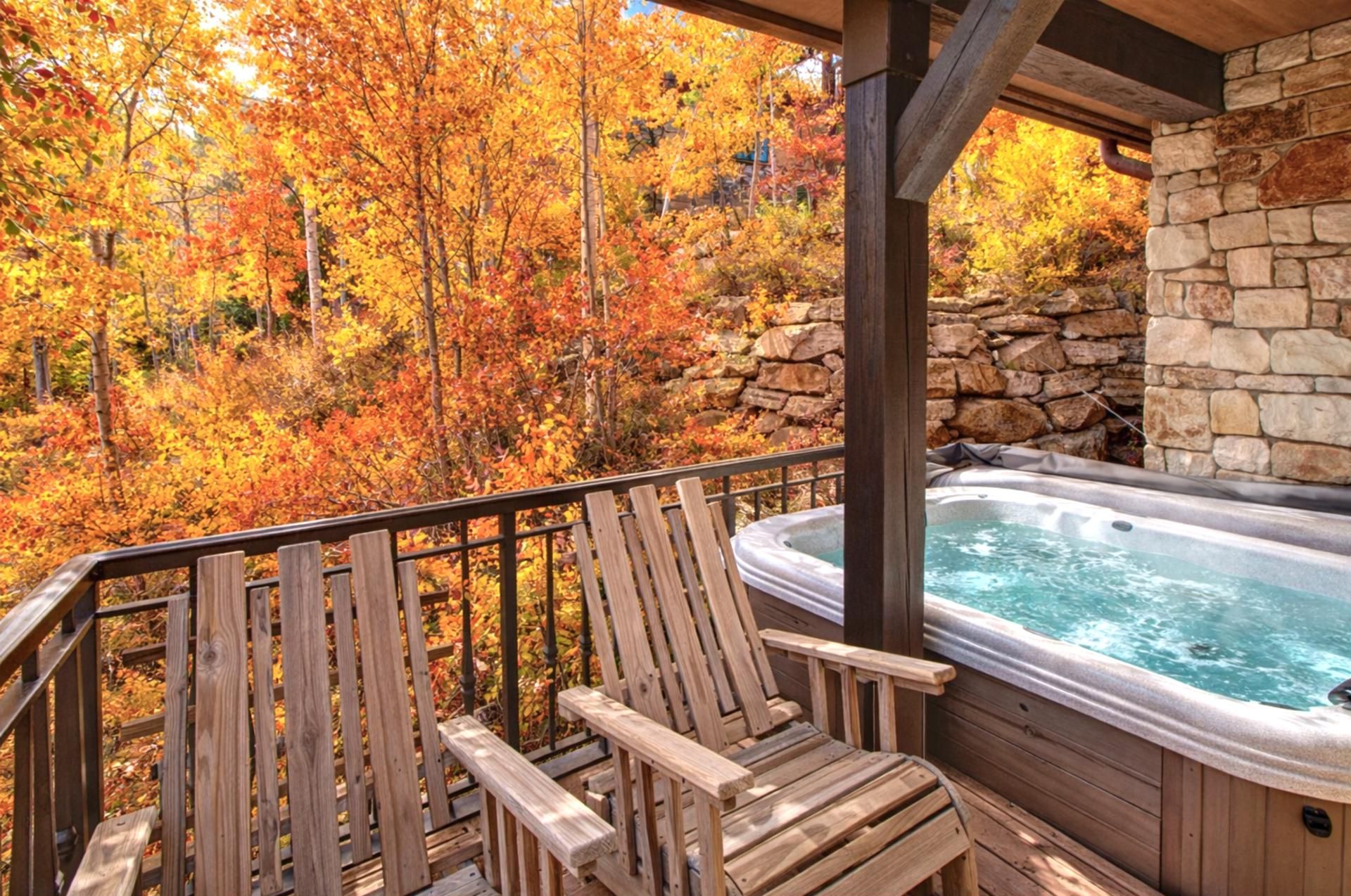 A wooden deck with two Adirondack chairs and a hot tub.
