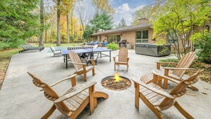 Eine Terrasse im Freien mit Adirondack-Stühlen, einer Feuerstelle und einem Tischtennisplatte.