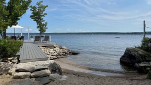 A wooden deck with outdoor seating, a white gazebo, and a rocky shoreline leading to calm water. - Private Lakefront Estate with 180 Degree Views (Raymond)