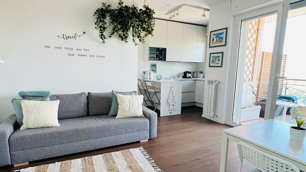 Un salon moderne avec un canapé gris, une table basse blanche et un tapis à rayures.