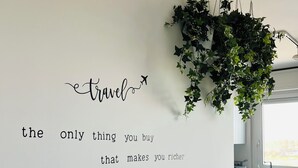 Un salon moderne avec un canapé gris, une plante suspendue et une citation inspirante sur le mur.