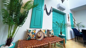 A cozy seating area with a woven bench, a potted plant, and a wall-mounted decorative item. - Beautiful 4 Bedroom Riad with Rooftop Terrace, Pool & Airport Shuttle Marrakech (Marrakesh)