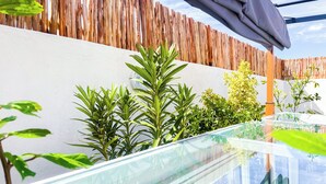 A modern outdoor area with a glass table, wooden fence, and various plants. - Beautiful 4 Bedroom Riad with Rooftop Terrace, Pool & Airport Shuttle Marrakech (Marrakesh)