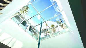A room with a large skylight, allowing natural light and views of palm trees and the sky. - Beautiful 4 Bedroom Riad with Rooftop Terrace, Pool & Airport Shuttle Marrakech (Marrakesh)